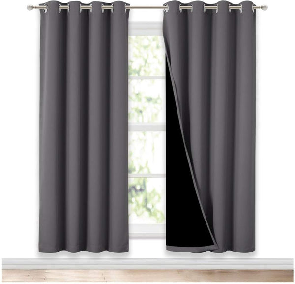 Dark grey blackout curtains with silver grommet tops, showing black lining, hanging over a window.