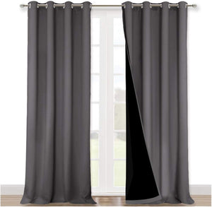 Dark grey blackout curtains with silver grommets hanging over a white door, revealing black thermal lining.