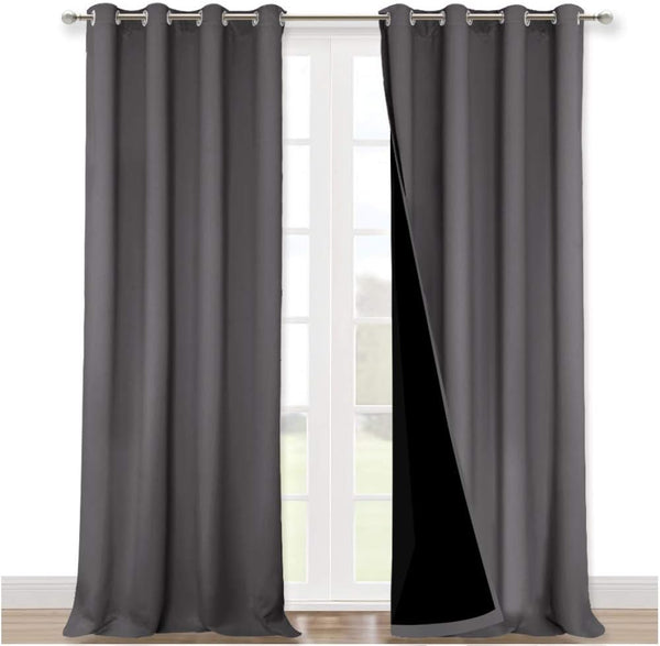 Dark grey blackout curtains with silver grommets hanging over a white door, revealing black thermal lining.