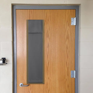 Dark grey rectangular privacy cover with visible stitching on a light wood door window.