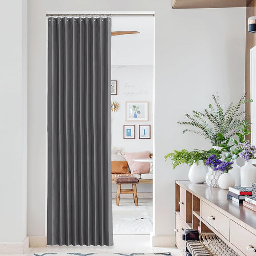 Dark grey pleated single curtain hangs on a silver rod in an interior doorway for privacy.