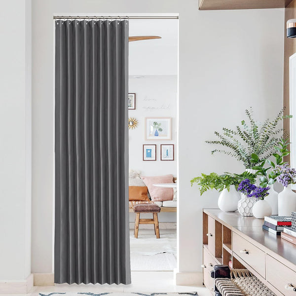 Dark grey pleated single curtain hangs on a silver rod in an interior doorway for privacy.