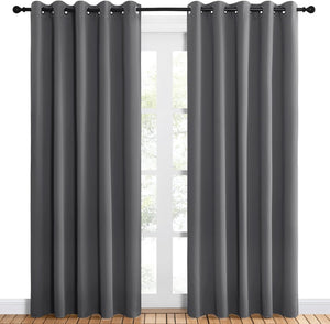 Pair of dark grey grommet top blackout curtains hanging over a white window.