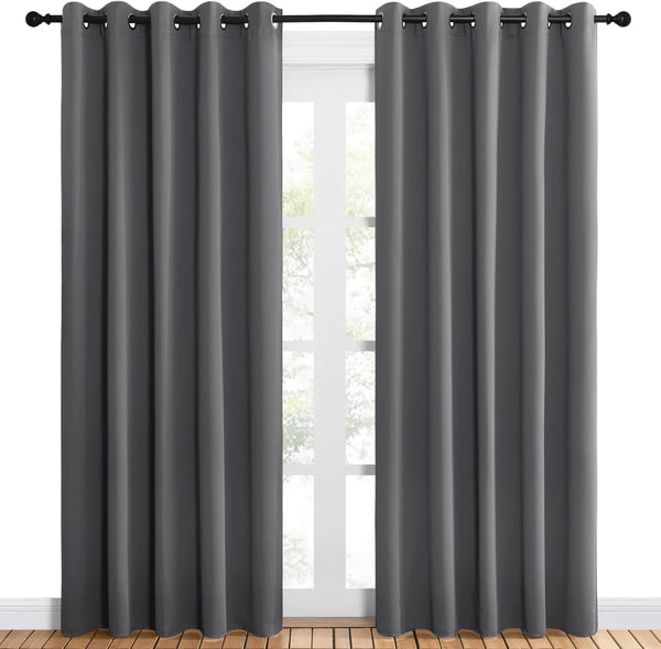 Pair of dark grey grommet top blackout curtains hanging over a white window.
