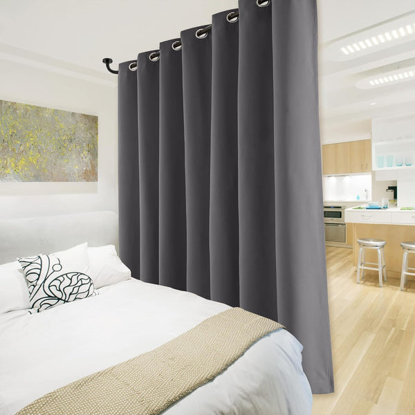 Dark grey grommet top privacy curtain acting as a ceiling-mounted room divider between a bedroom and kitchen.