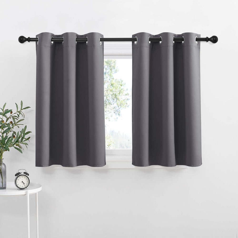 Pair of dark grey grommet top tier curtains on a black rod, partially covering a window.