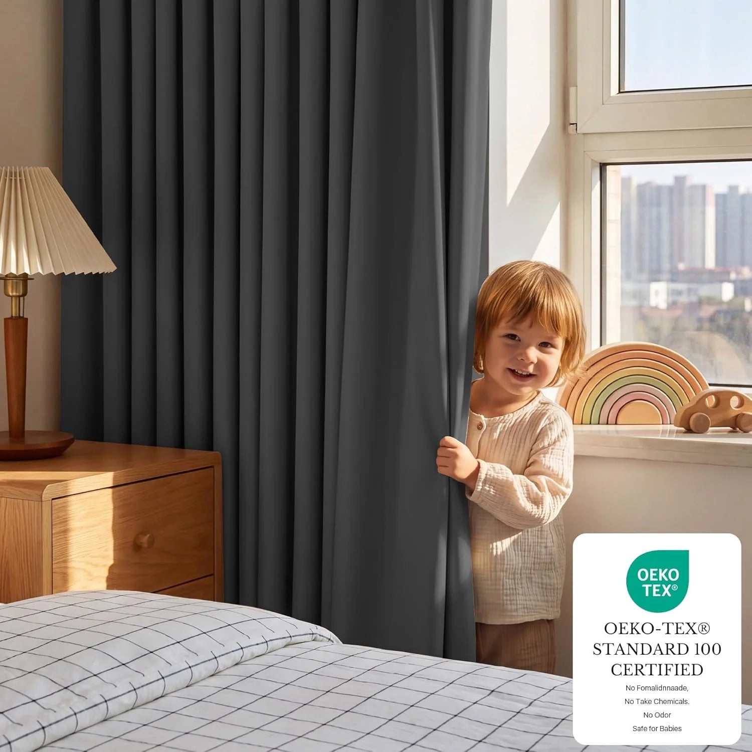 Smiling toddler peeks from dark grey blackout curtain in bright nursery with wooden toys.