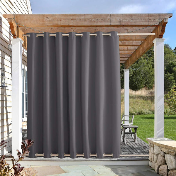 Dark grey outdoor curtain with metal grommets hangs from a wooden pergola on a sunny patio