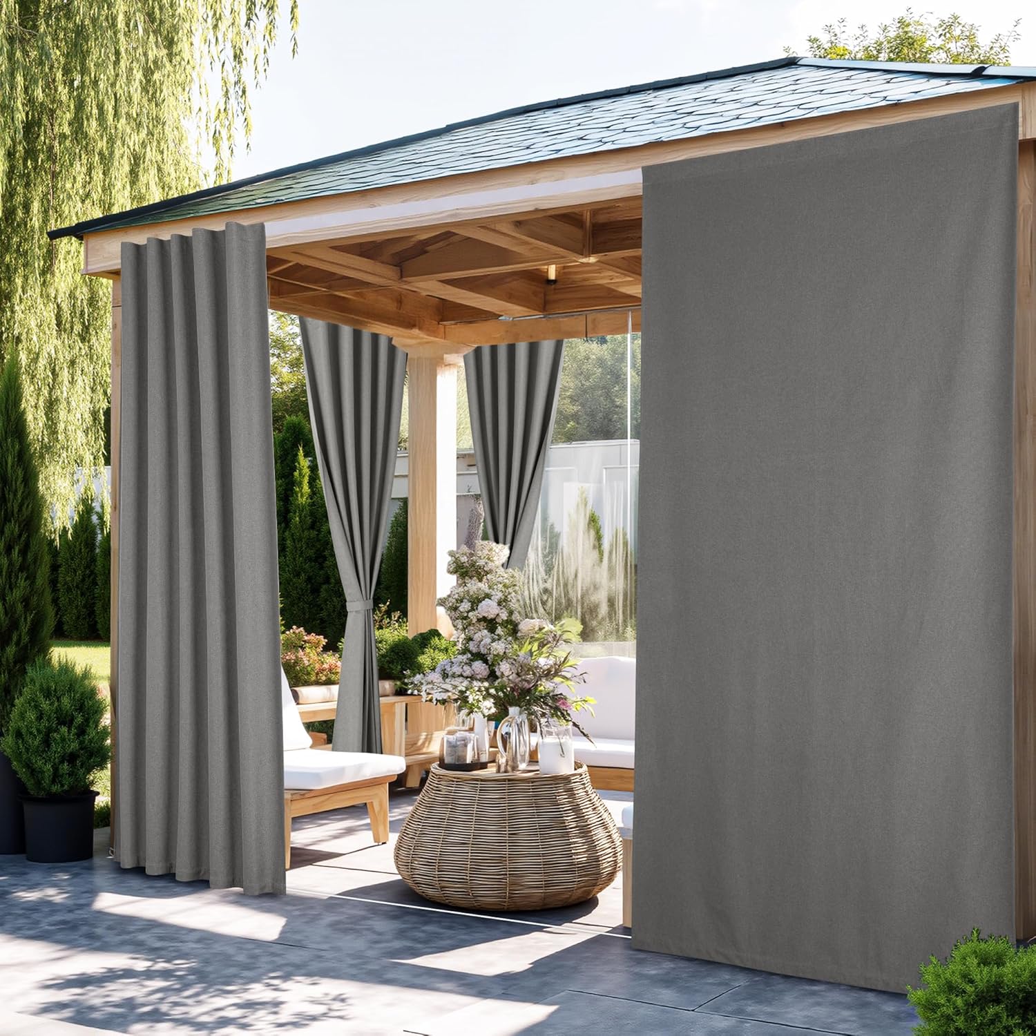 Dark grey outdoor drapes hanging on a wooden pergola, providing privacy to a patio seating area.