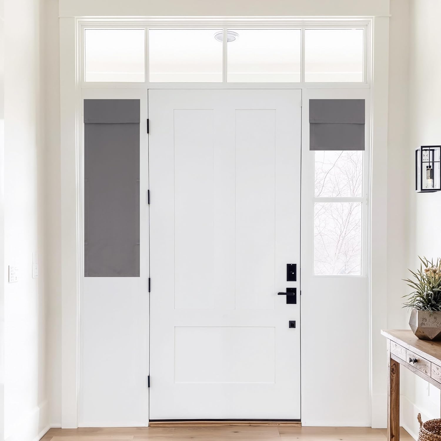 Dark grey fabric roman shades covering sidelight windows beside a white front door.