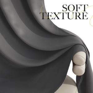 Close-up of a dark grey, soft texture curtain fabric with elegant folds, draped over a light beige surface.