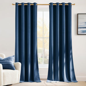 Pair of deep blue velvet window curtains with gold grommet tops on a golden rod in a sunlit room.