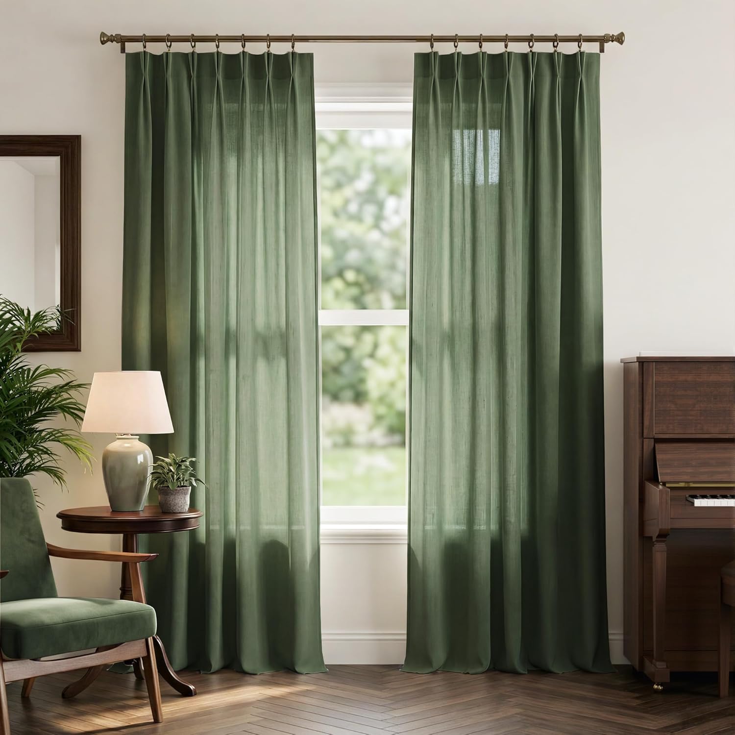 Deep green linen pinch pleat curtains hang on a bronze rod, softly filtering light in a living room.