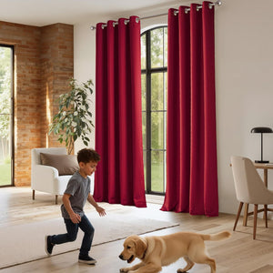 Deep red grommet top curtains with silver rings elegantly cover large windows in a modern living room.