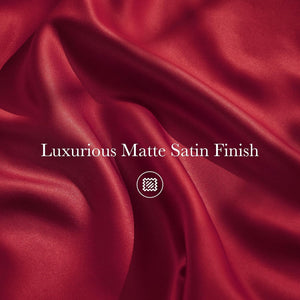 Close-up of luxurious deep red matte satin fabric with soft, flowing folds and a subtle sheen.