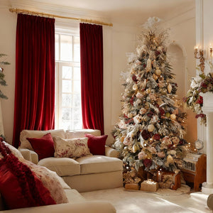 Deep red velvet pinch pleat curtains on a decorative gold rod in an elegant Christmas living room.