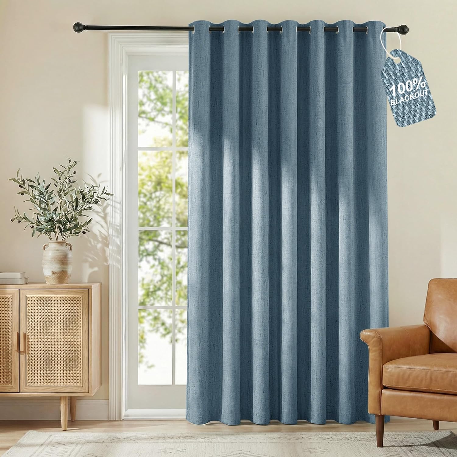 Denim blue textured blackout curtain with metal grommets, hanging in a bright living room.