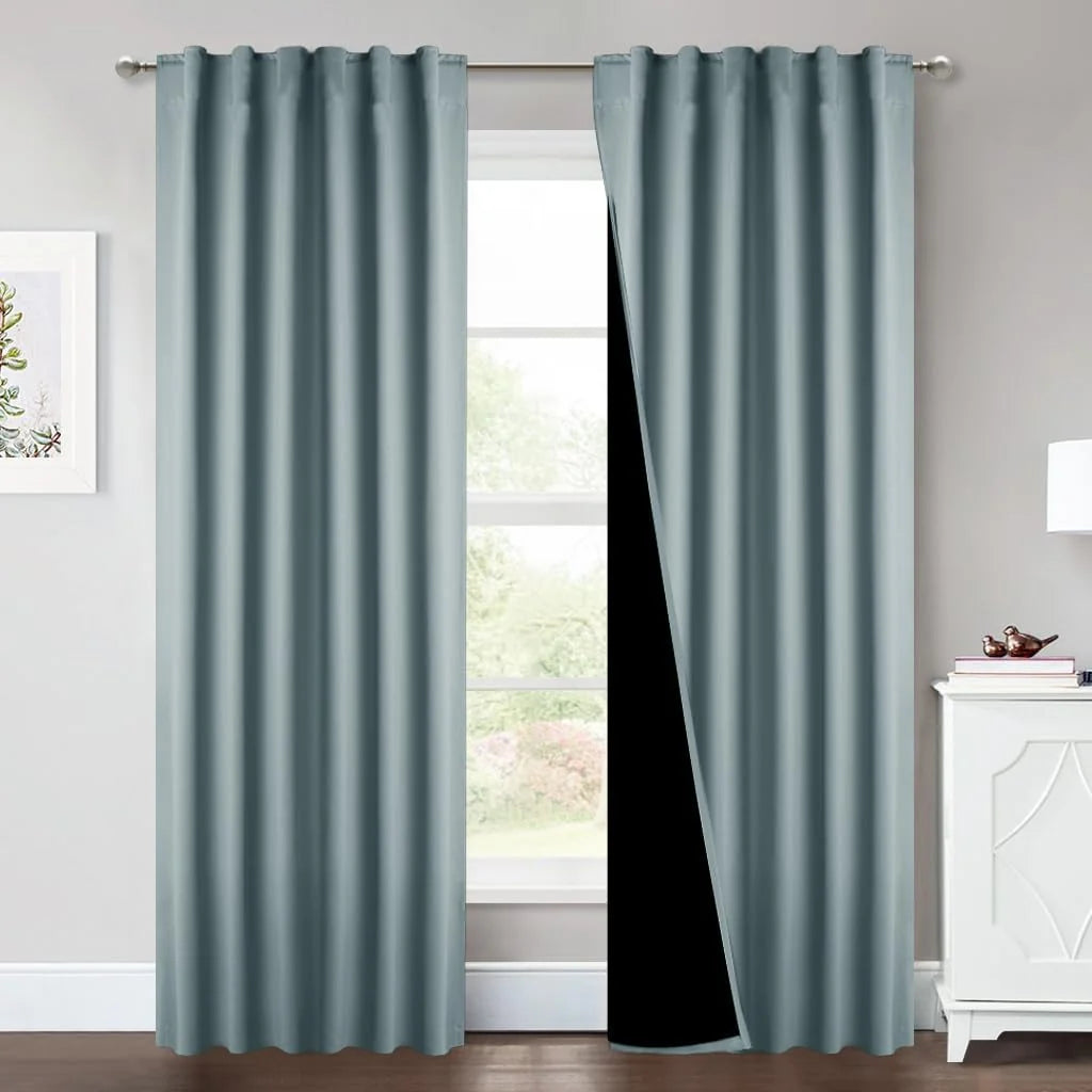 Duck egg blue blackout curtains with pleated top hanging on a silver rod by a bright window