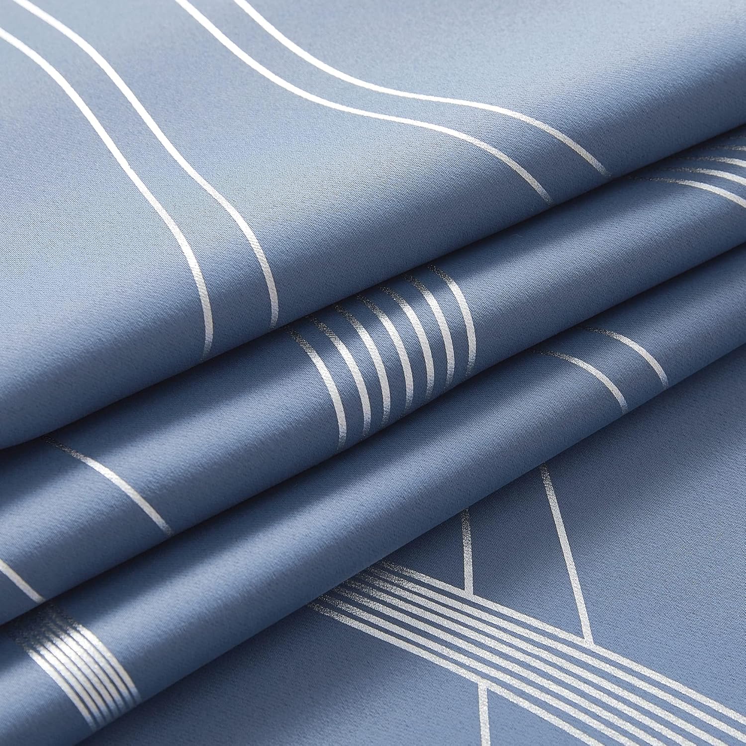 Close-up of dusty blue textile with reflective silver geometric wavy and straight line patterns, folded.