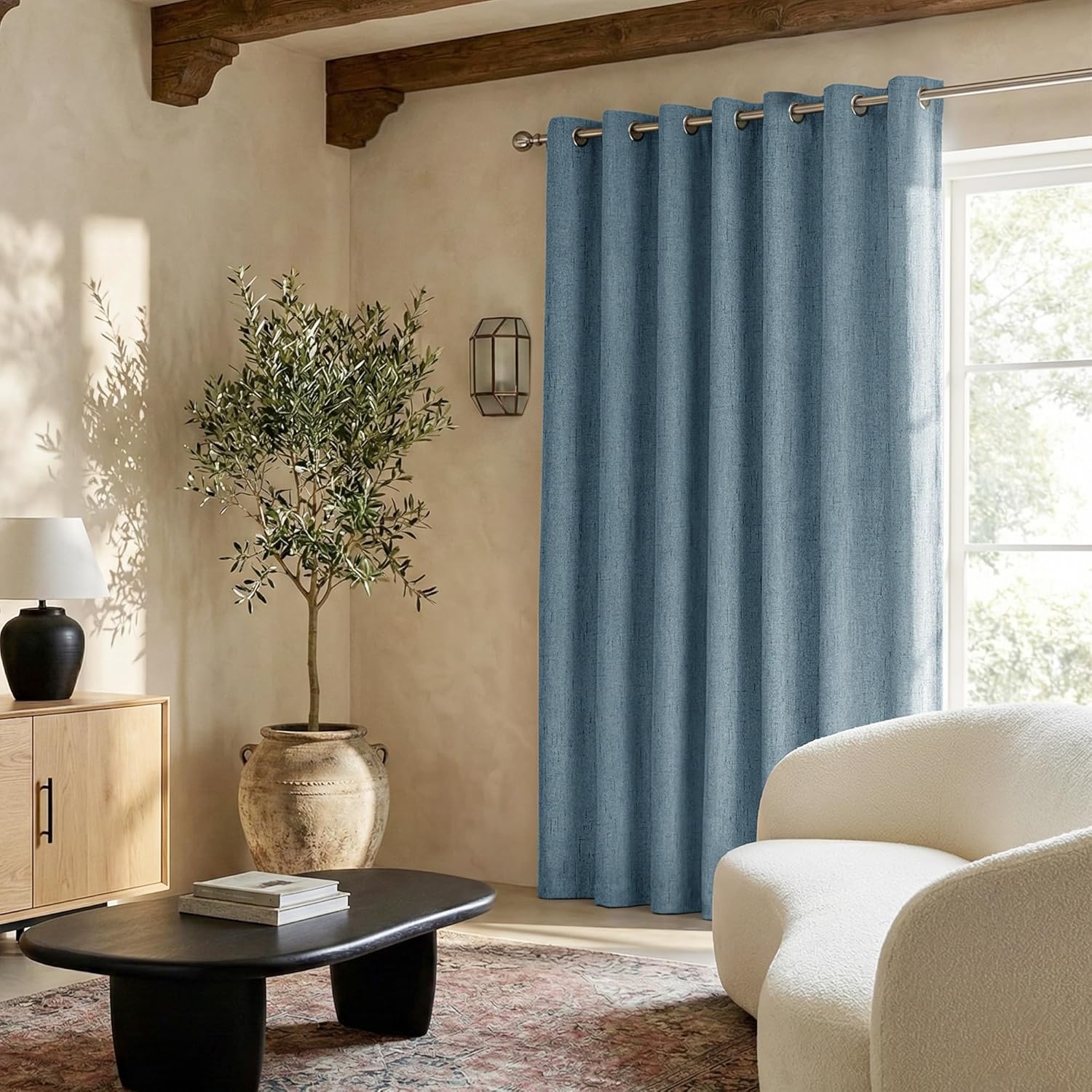 Dusty blue textured grommet top blackout curtain panel hanging in a sunlit room