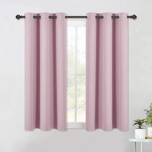 Two panels of dusty pink blackout curtains with metallic grommet tops hanging over a window.