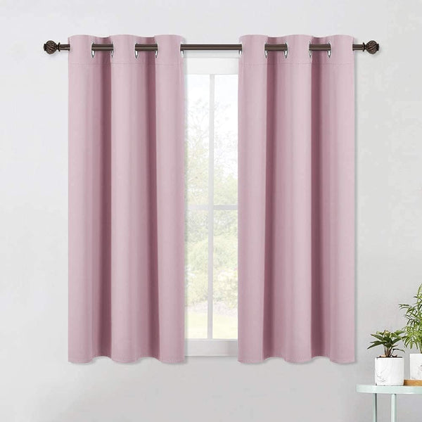 Two panels of dusty pink blackout curtains with metallic grommet tops hanging over a window.