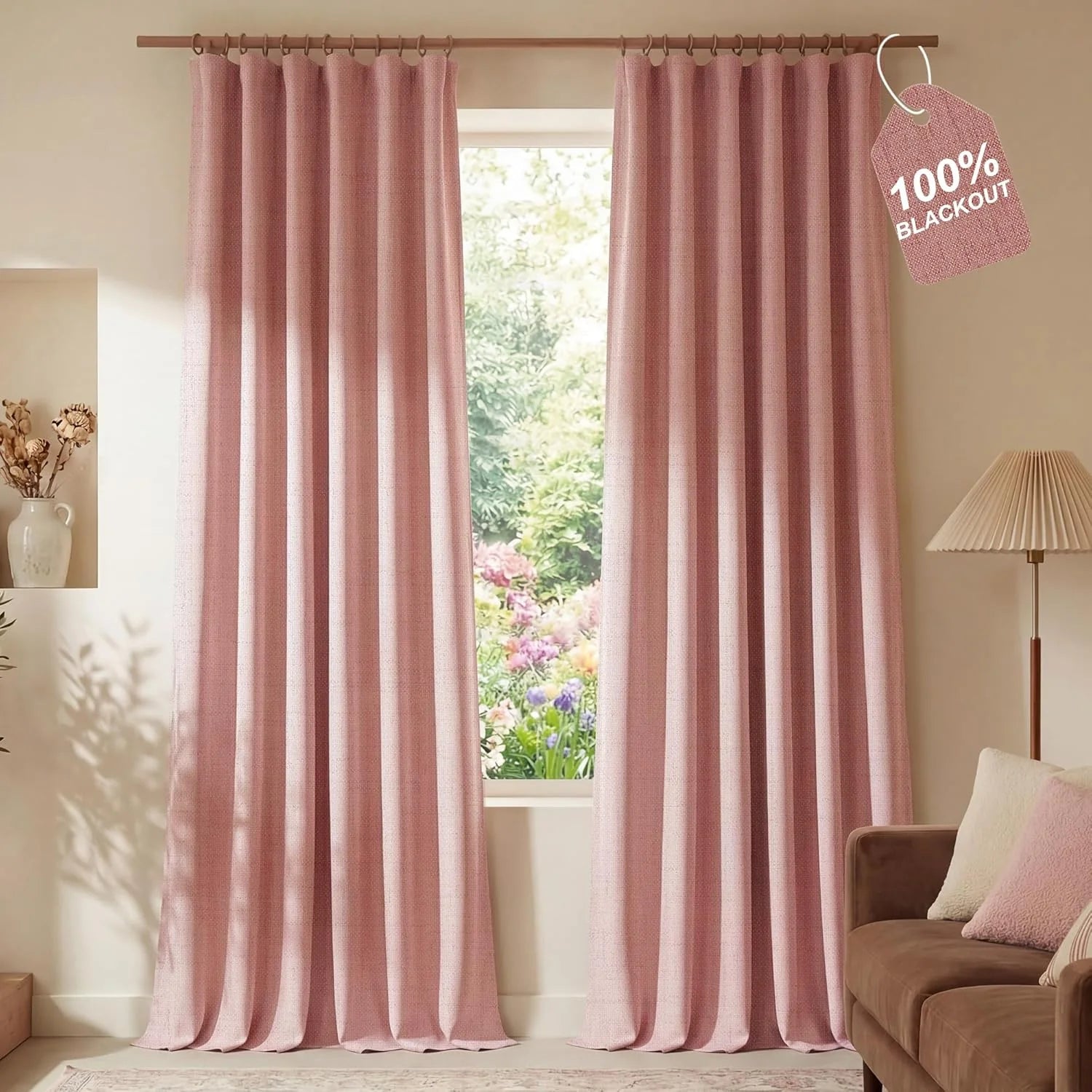 Dusty pink textured blackout curtains hanging on a wooden rod in a cozy living room with a garden view.