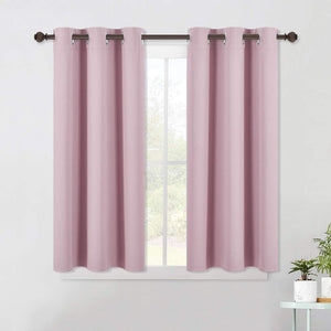 Pair of dusty pink blackout curtains with silver grommets hanging on a dark rod over a window.