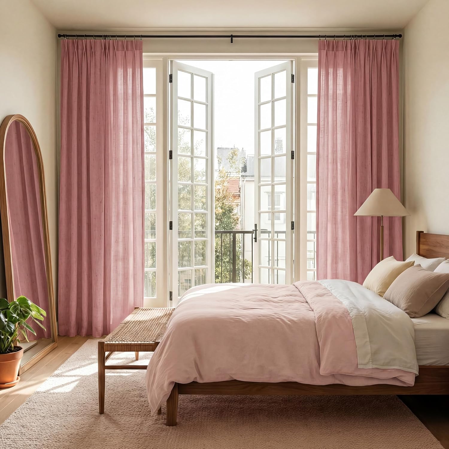 Textured dusty pink linen curtains hung in a bright bedroom with matching bedding on a wooden bed frame.