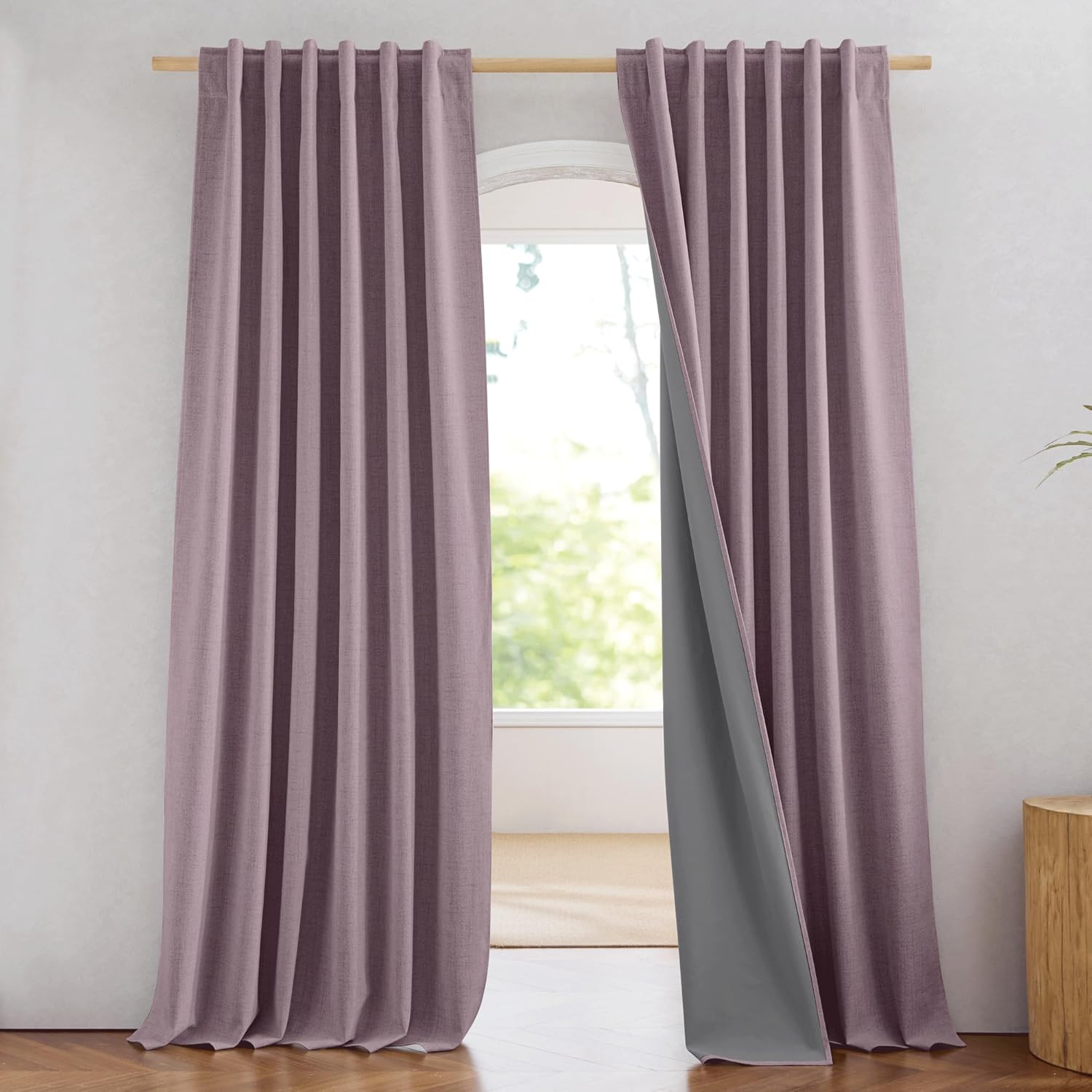 Dusty rose textured blackout curtains with grey lining and pinch pleat top on a wooden rod.