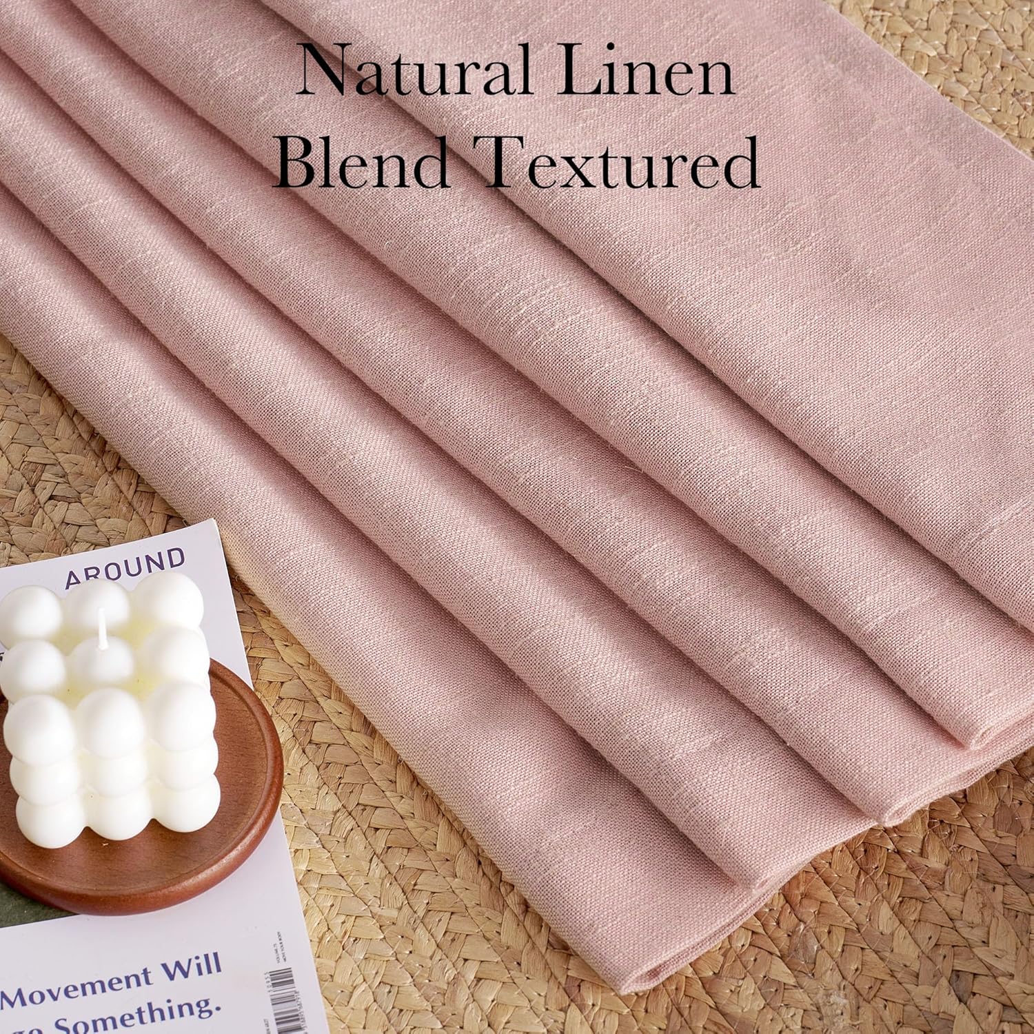 Dusty rose natural linen blend textured fabric, folded, on a woven straw mat.