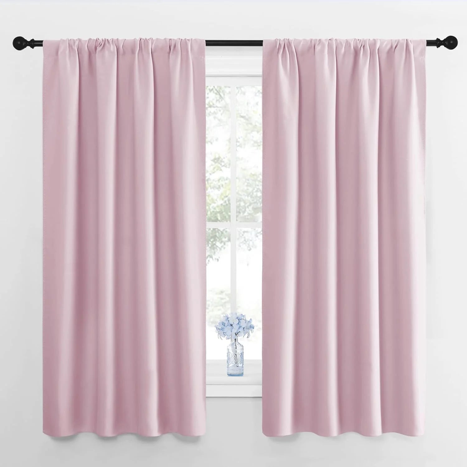 Pair of dusty rose pink rod pocket curtains on a black rod over a window.