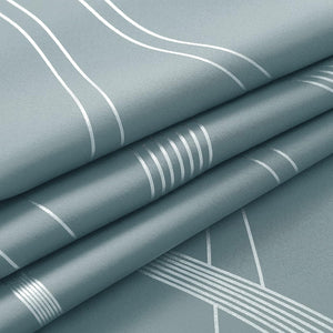 Dusty teal fabric with shiny silver geometric lines, folded to display the unique pattern and subtle woven texture.