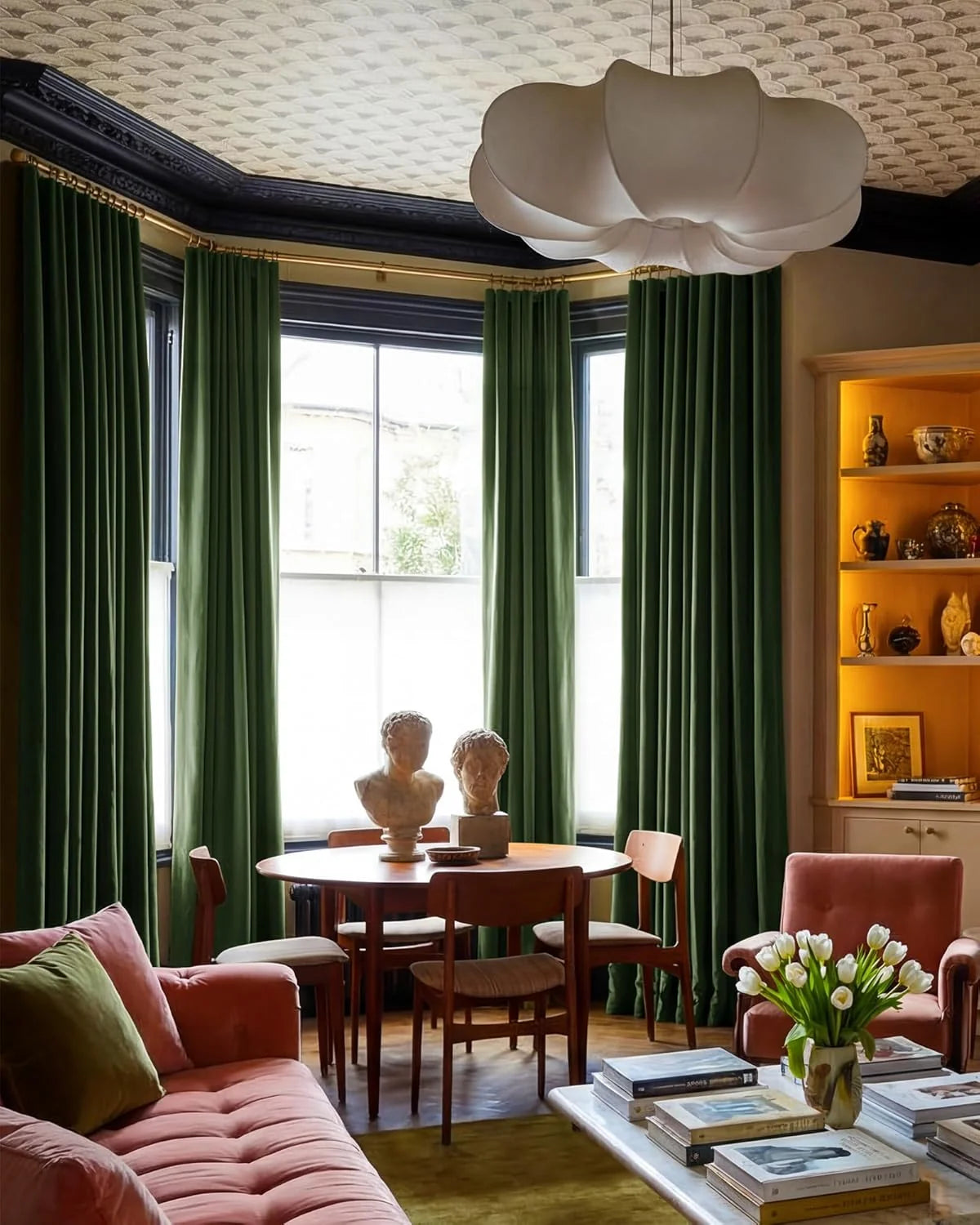 Emerald green velvet curtains in a stylish living room with pink seating and wood table