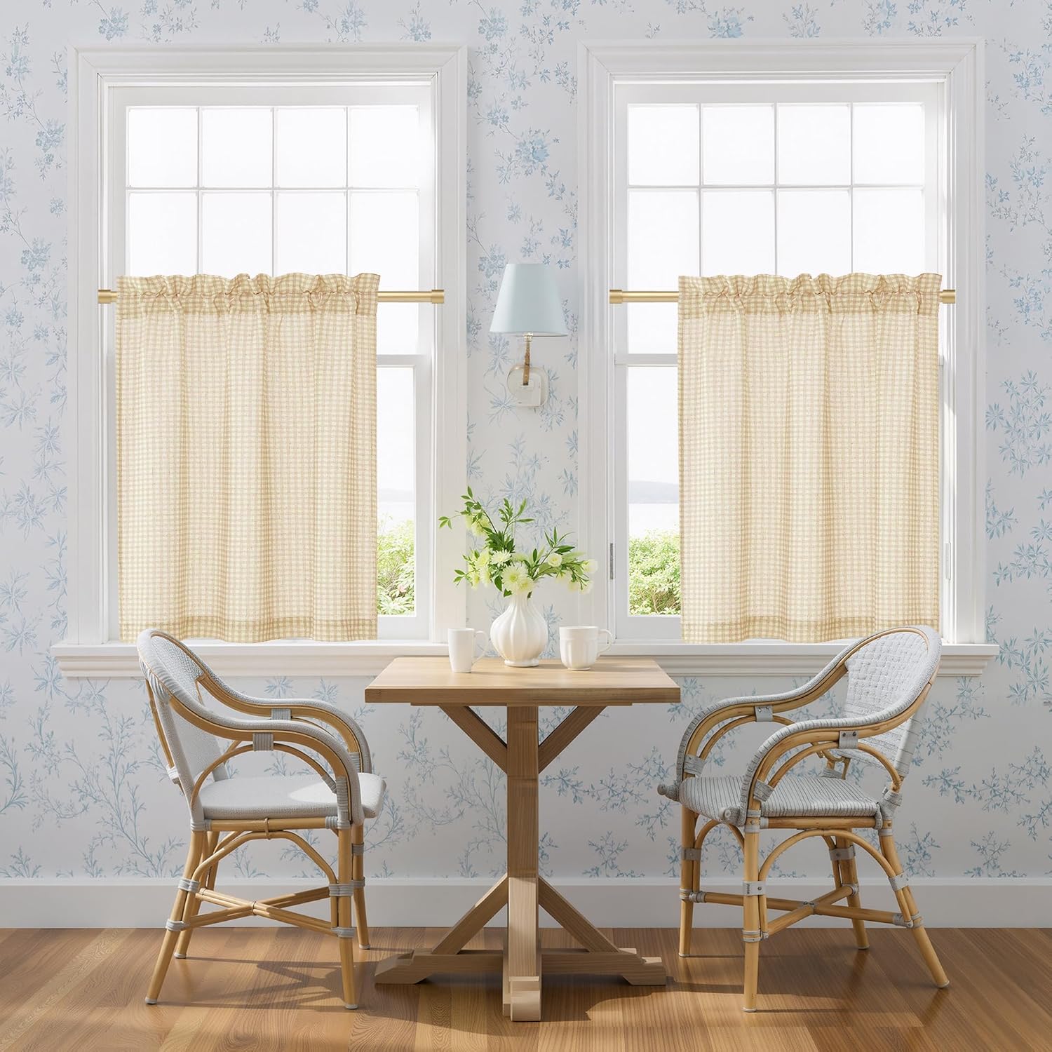 Farmhouse beige gingham cafe curtains with rod pocket top on golden rods in sunny window.
