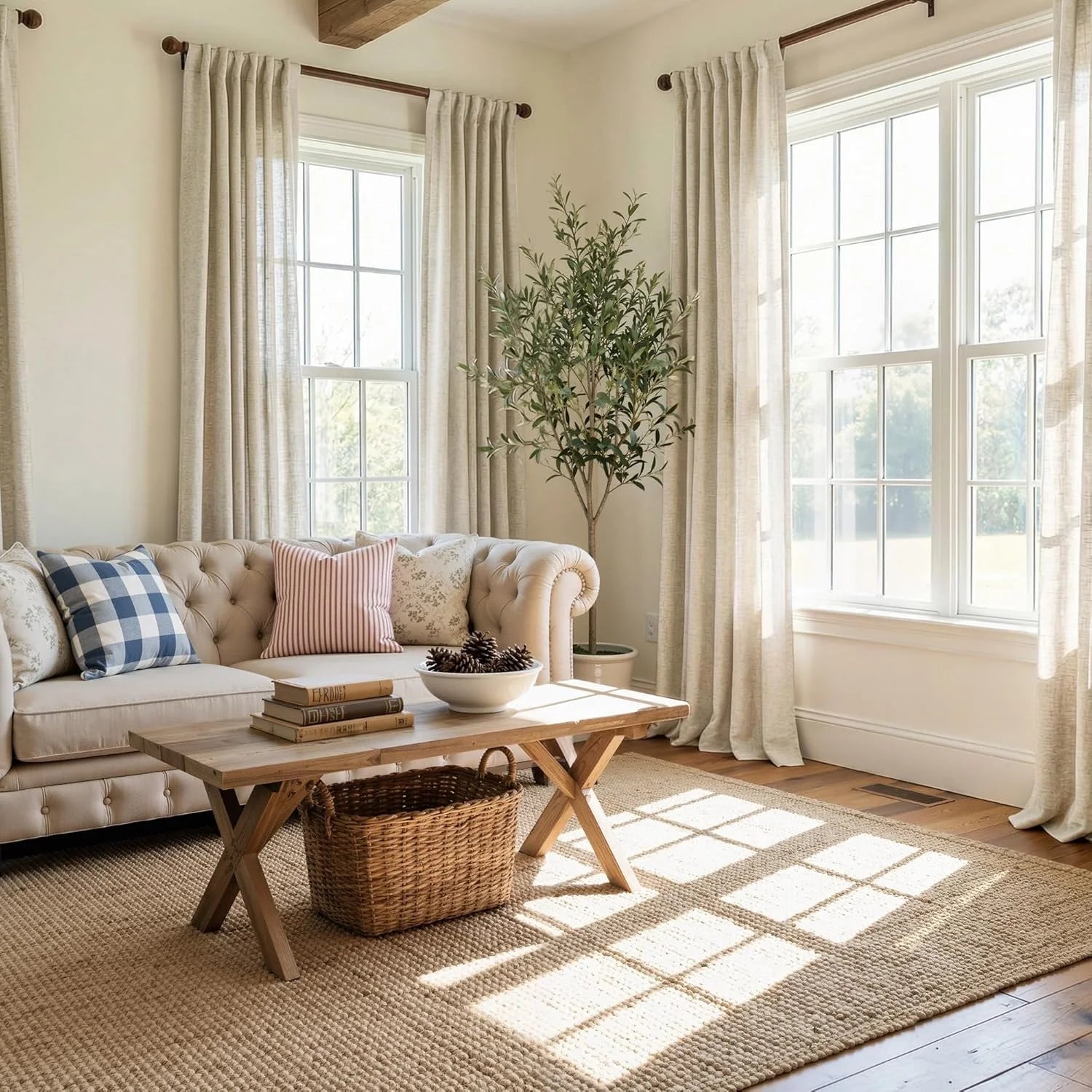 Bright farmhouse living room with neutral linen curtains, beige tufted sofa, and woven jute rug.