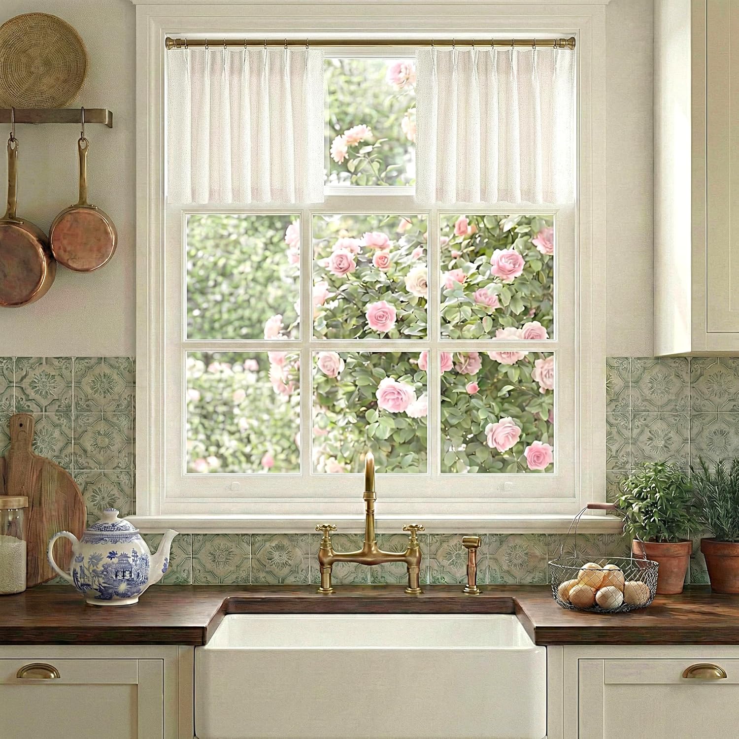 Sheer white cafe curtain with delicate dot pattern hangs on a brass rod in a cozy kitchen window.