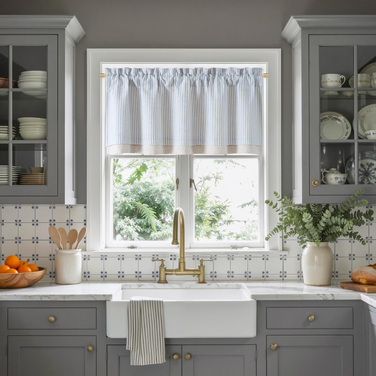 Gathered light blue and white striped valance with natural linen bottom band, in a kitchen window.