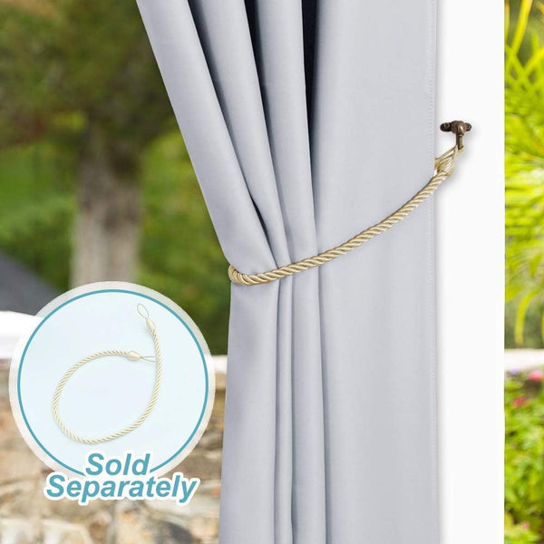 Light gray blackout curtain held open by a decorative gold braided rope tie-back hooked to wall.