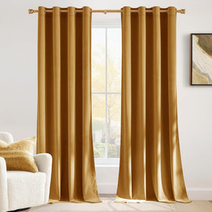 Elegant gold velvet grommet top curtains hanging on a brass rod, framing a bright window.