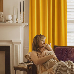 Vibrant golden yellow blackout curtain with neat pleats beside a window.