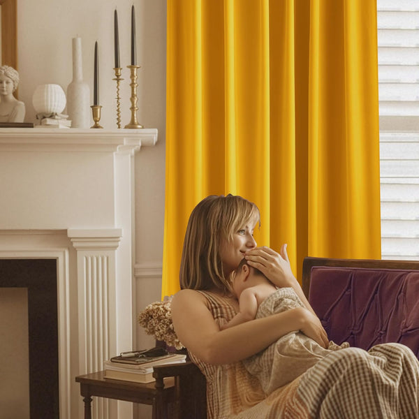 Vibrant golden yellow blackout curtain with neat pleats beside a window.