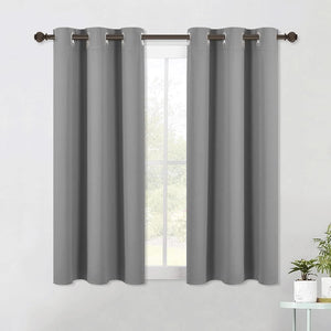 Pair of gray blackout curtains with silver grommet tops hanging on a dark metal rod over a window.