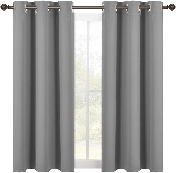 Two solid gray blackout curtain panels with silver grommets hang on a dark bronze rod in front of a window.