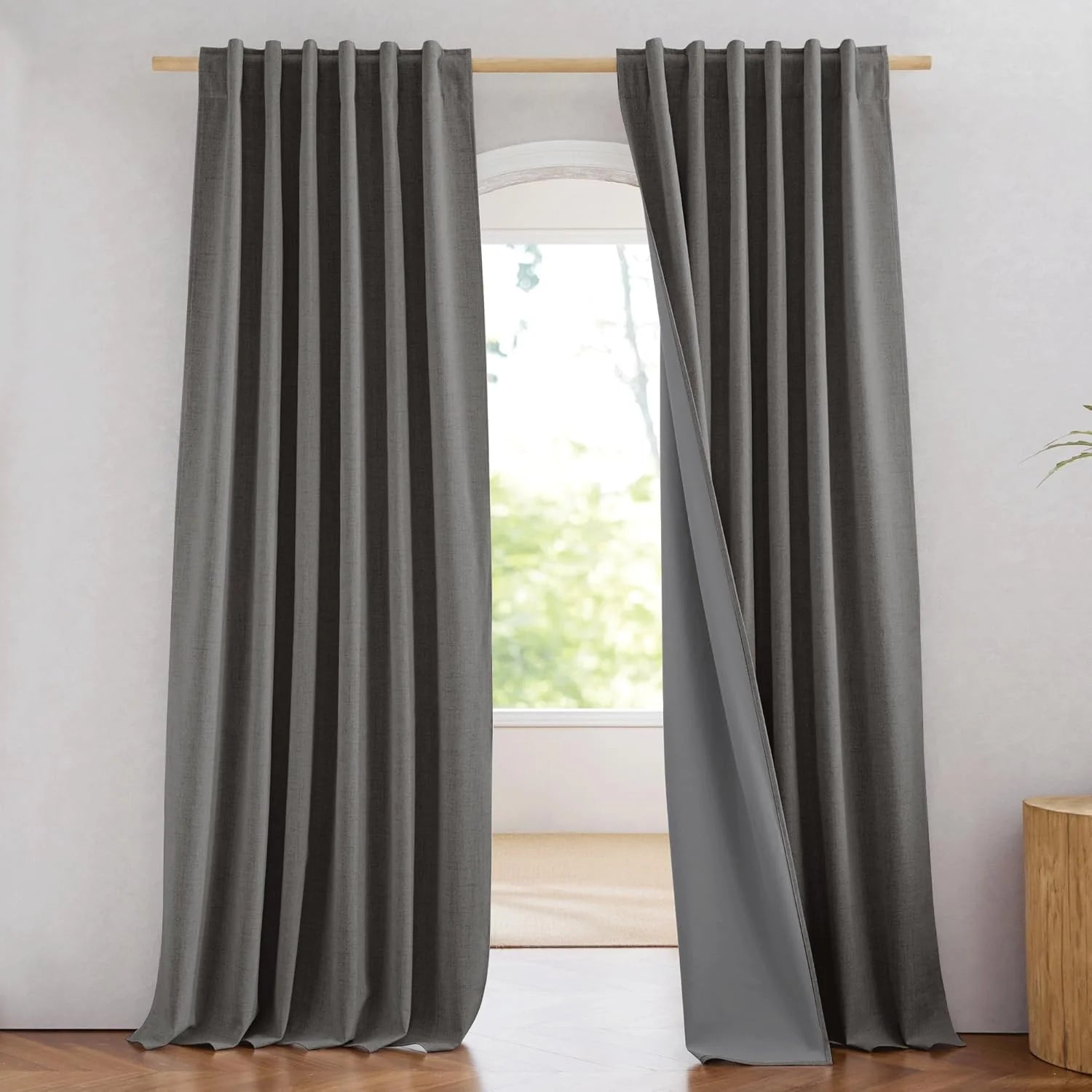Gray linen-look blackout curtains with pleated header hanging on a wooden rod
