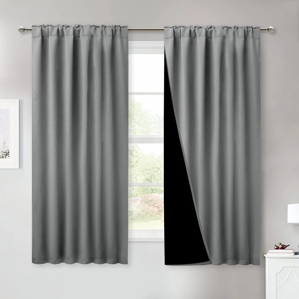 Gray blackout curtains with pencil pleat header on a silver rod in a bright room