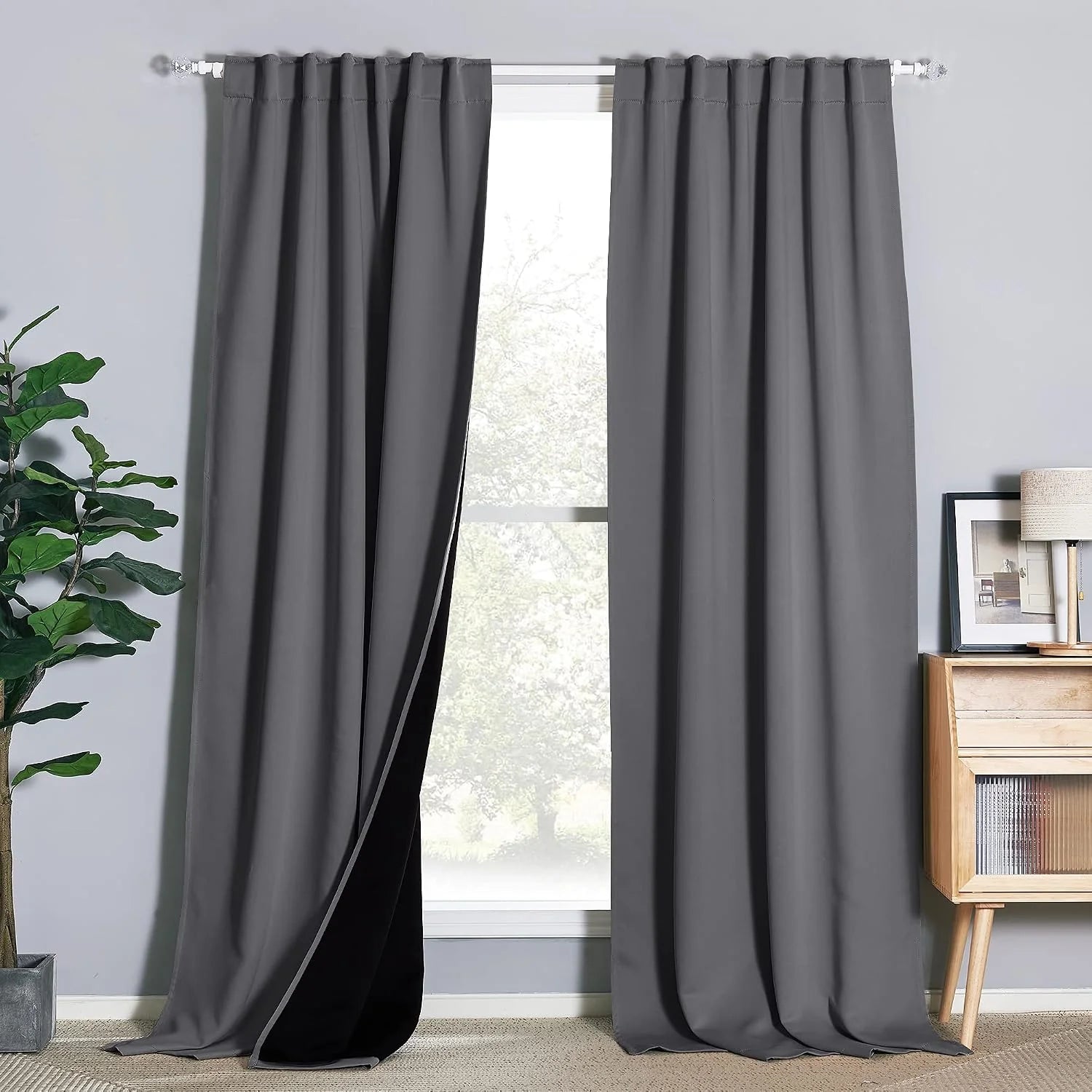 Dark gray blackout curtains with rod pocket top hanging in a bright modern room