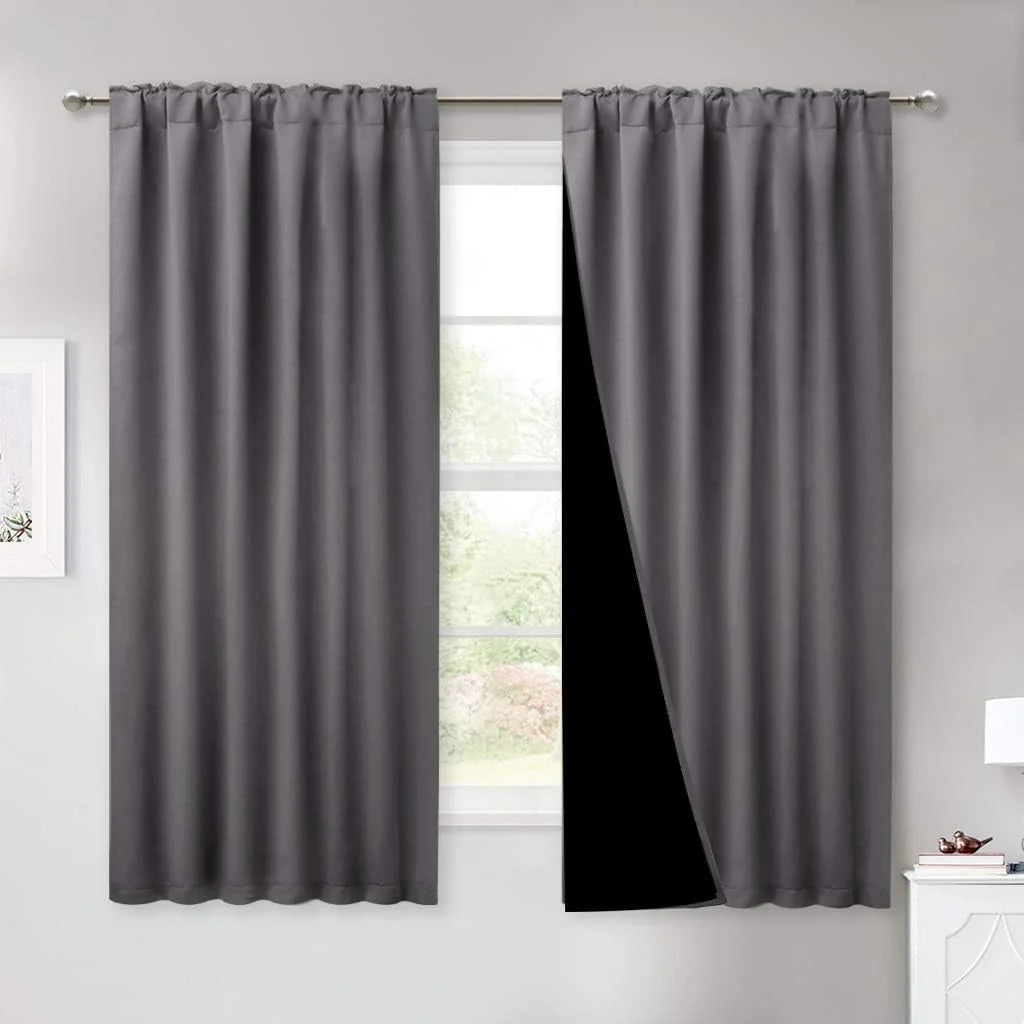 Gray blackout curtains with rod pocket top hanging over a bright bedroom window