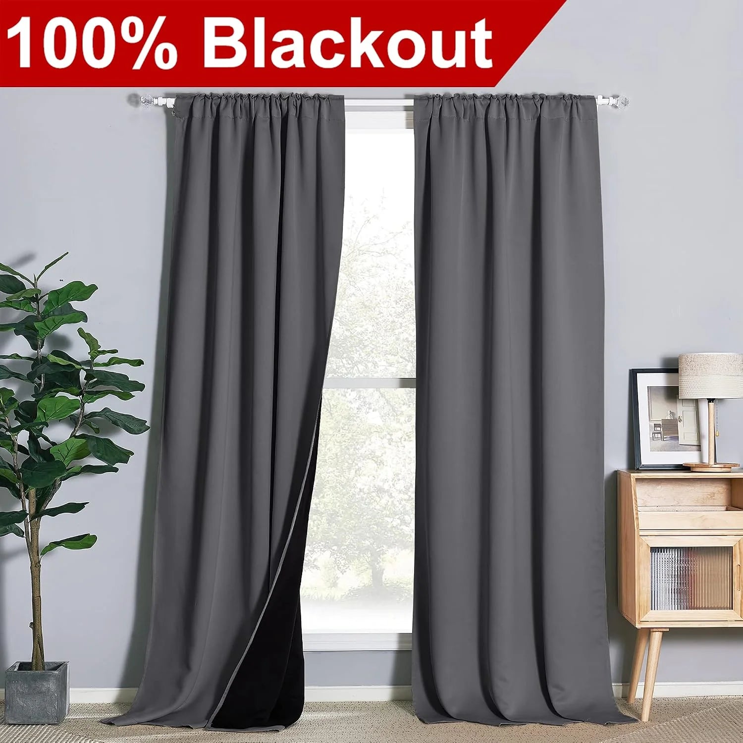 Gray blackout curtains on a rod in a modern room with plant and wood cabinet