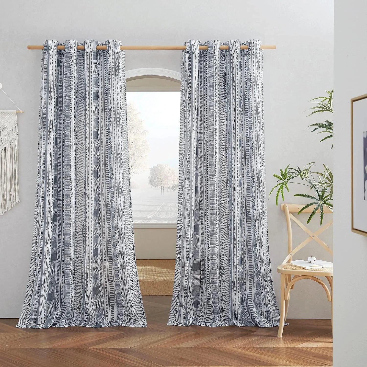 Gray and white boho geometric curtains hanging on a wooden rod in a bright room